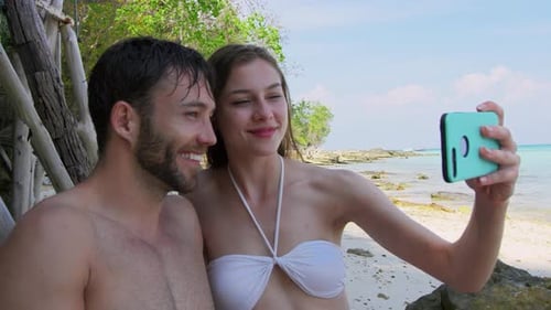Carefree couple capturing memories with smartphone on a Thailand beach adventure