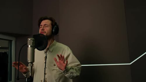 singer with headphones and microphone emotionally recording a new song in a professional studio