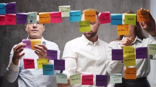 Team of Business People is Doing Brainstorm at a Meeting Using Stickers on the Glass Office Workers