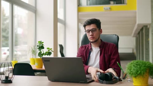 Man Finishing Work on Laptop in Bright Office