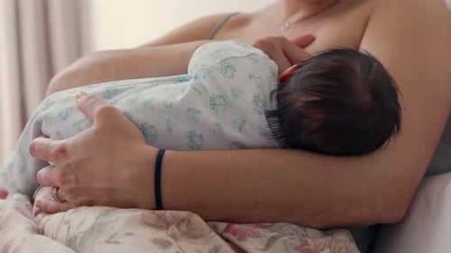 Mother breastfeeding her newborn while cradling the baby close in bed. the warmth, security, and