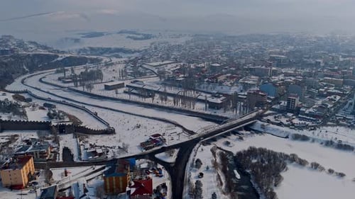 Una ciudad con un río que la atraviesa y nieve en el suelo