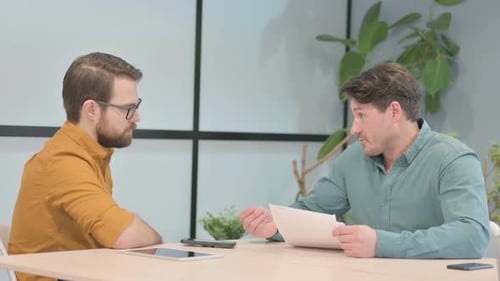 Men Discussing Corporate Documents in Office Setting