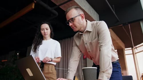 Diverse colleagues stand near the desk looking at the computer screen.