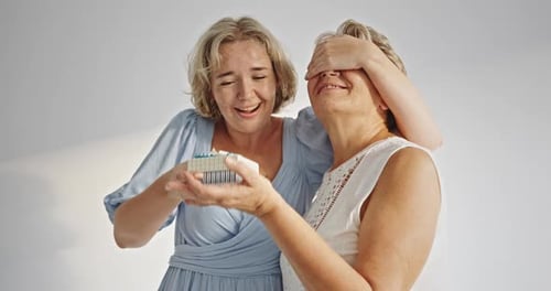 Woman Presents Gift to Senior Woman for Birthday