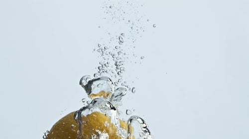 Lemon Falls Into Water Creating Bubbles