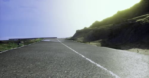 Scenic Coastal Road Surrounded By Cliffs and Bright Sky at Sunset