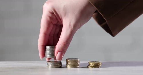 Woman stacking coins at wooden table, closeup