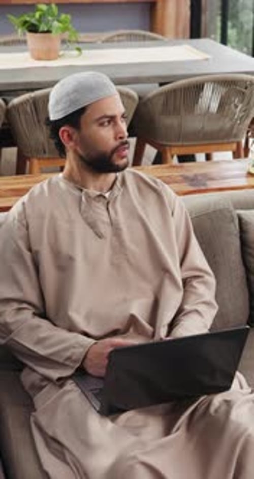 Musulman, homme et télétravail à domicile avec un ordinateur portable, recherche ou dactylographie d'un reportage pour un travail de journaliste