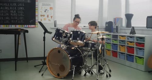 Teacher and Boy Drumming in Music Classroom