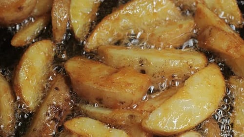 Making Fried Potato Wedges Country Potatoes in a Pan in Boiling Oil Closeup Potato Pieces Snack Food