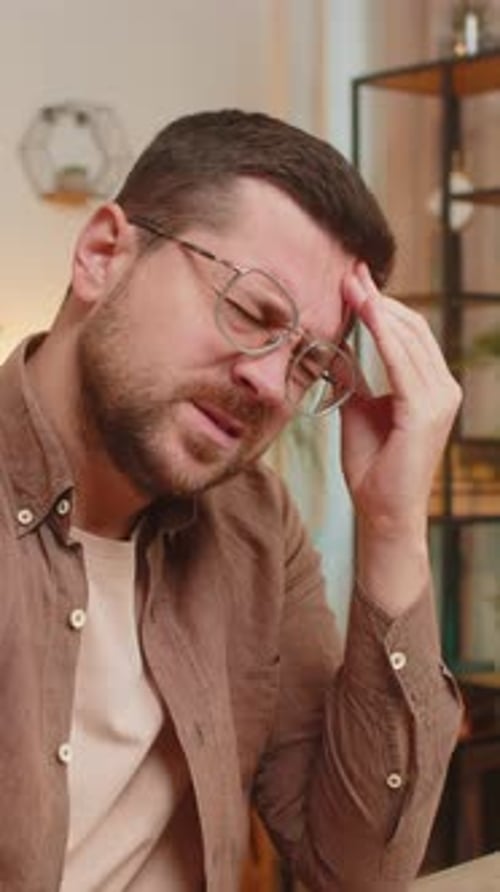 Man with Headache at Desk Holding His Head