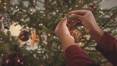 Hands Hang Ornament on Decorated Christmas Tree