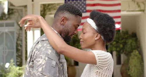 Loving Military Couple Embraces in Front of Home