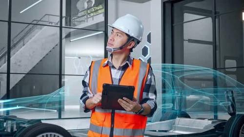 Asian Male Engineer Looking At The Tablet In His Hand With Concept of Electric Vehicle