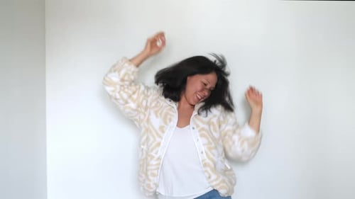 Cheia de energia, uma mulher dança alegremente em uma sala bem iluminada, expressando seu movimento dinâmico