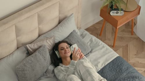 Woman Relaxing in Bed Listening to Music