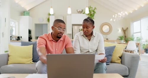 Couple Looking at Laptop on Couch Indoors