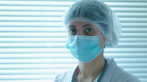 Woman in Mask and Cap in Hospital