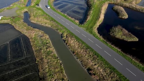 Drone Footage of a Car Driving on a Narrow Road Between the Salt Marshes