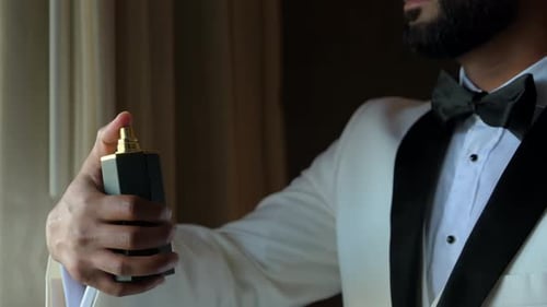 Close Up View of Man in White Suit Spraying the Perfume on Himself Slow Motion