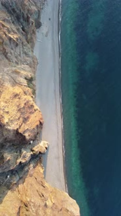 Aerial Vertical View of Beach with Wave Caressing Shore Sun Glare Small Waves on the Water Surface