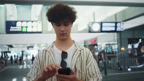 Traveler Examines Flight Info Man in Striped Shirt Consults Flight Information at Busy Terminal Male