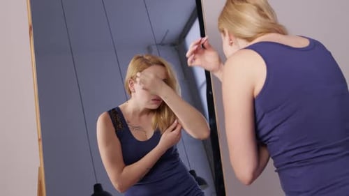 Woman Styling Blonde Hair in Front of Mirror
