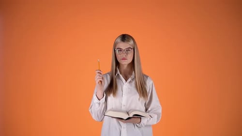 Thoughtful Young Blonde Woman, Holding Pencil and Book, Colorful Studio Shot