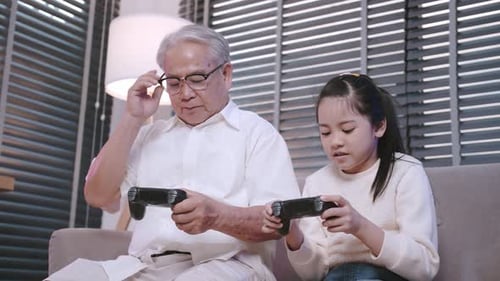 Child and Grandparent Play Video Games Together Indoors
