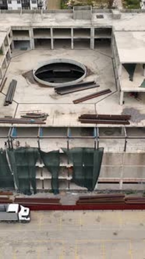 Vídeo vertical: Expedición aérea a un centro comercial: constructores de construcción arreglando vigas metálicas
