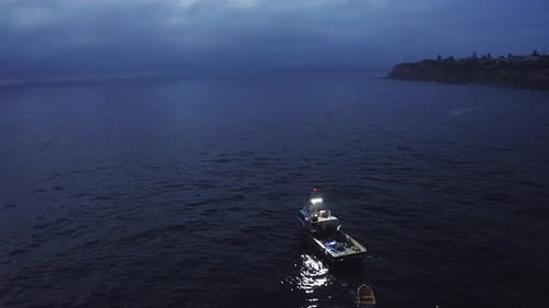 4k aerial drone footage of two men on a boat at sea in the evening