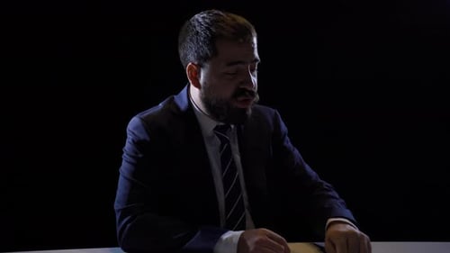 Man in Suit Talking and Gesticulating at Table