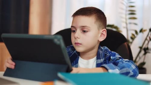 School Boy Looking at Camera While Using Digital Tablet During Homeschooling