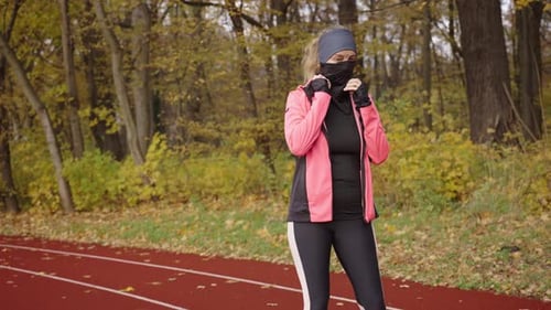 Female Runner Prepares to Run Puts on Sports Clothes on the Stadium Treadmill
