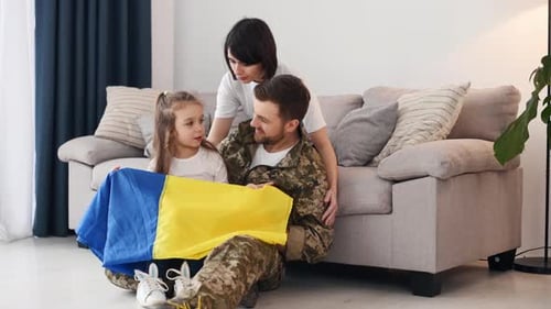 Military Man with Family Holds Blue and Yellow Flag
