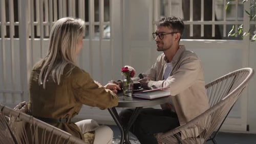 Couple Enjoying Coffee and Conversation at Outdoor Cafe