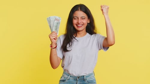 Woman Holding Cash Money on Yellow Background