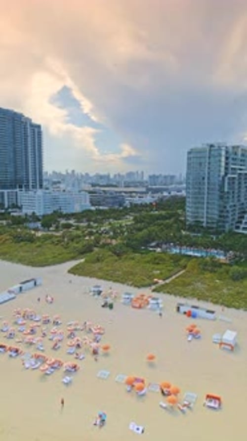 Vertical aerial view over Miami Beach, Florida, capturing in 4K the white sands lined with colorful