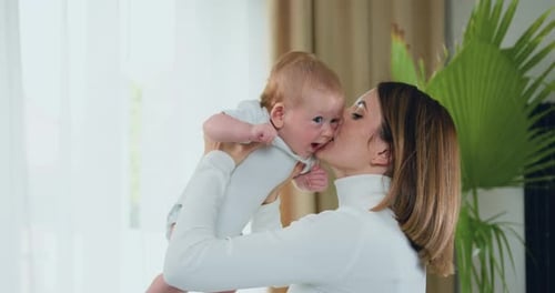 Woman Holds Smiling Infant Up in Natural Light
