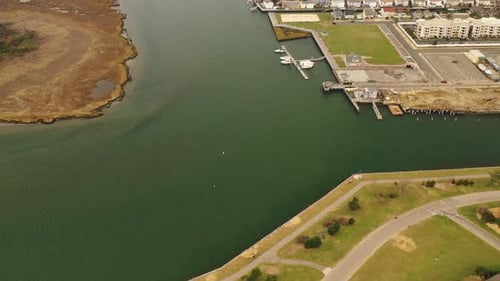 A high angle shot over a salt marsh area with parks with green grass near by. The camera dollys in a