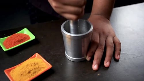 Der Koch mahlt das Garam Masala mit Stößel, Set für die Zubereitung von Speisen