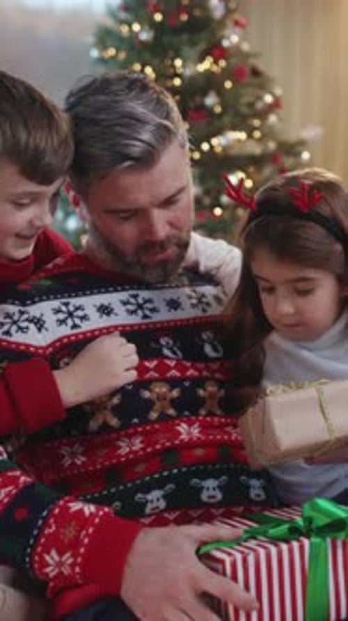 Father with Children Opening Christmas Gifts by Tree