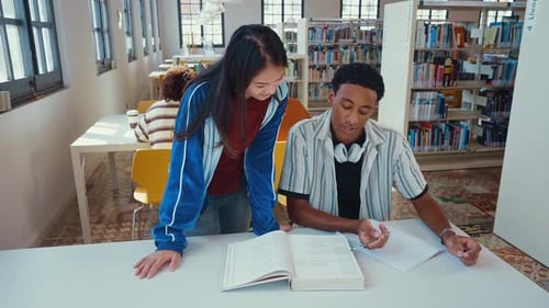 Junge und fröhliche multiethnische Studenten in der Bibliothek