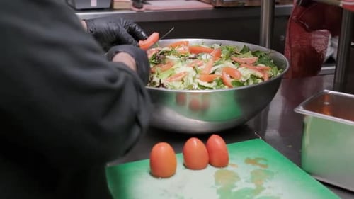 Man putting sliced tomatoes in a salad bowl