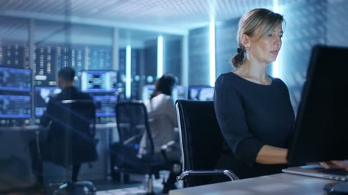 Female IT Engineer Works on Her Desktop Computer in Government Surveillance Agency. In the Backgrou