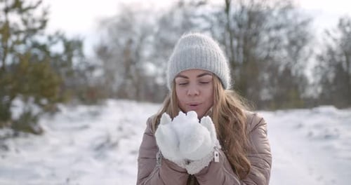 Woman Blowing Snow From Her Hands in the Forest