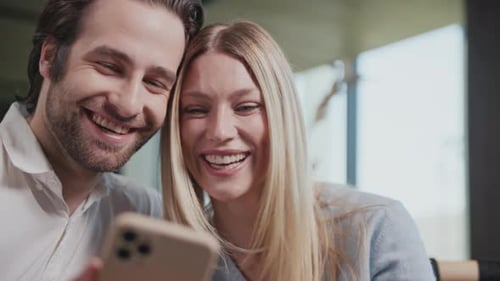 Lovely Happy Couple with a Smartphone in a Cafe Talking Smiling Sitting Modern Interior Have