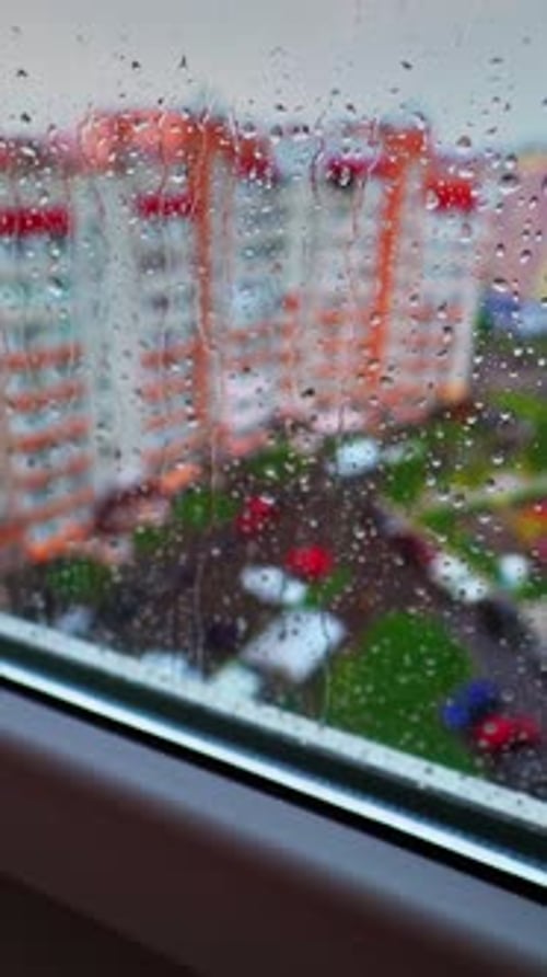 View through the window on raining weather. Drops of rain on a window pane on the city