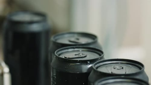 Wet black aluminum cans on conveyor belt in factory